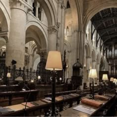 the interior of a large cathedral with many tables and lamps on each side of it