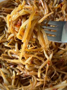 a close up of a plate of food with noodles and cheese on it, with a fork in the bowl