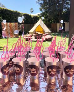 there are many cups on the table with pink straws in them and some balloons