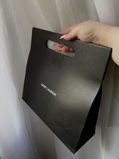 a woman's hand holding a black shopping bag