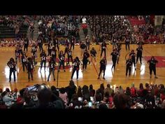 a group of people standing on top of a basketball court in front of a crowd