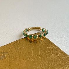 18KT yellow gold ring with round, genuine, bezel-set, emeralds band ring. Great for stacking, wedding band, anniversary, birthstone etc... Totally adjustable to wear on different size fingers! Weight: 1.2 grams Adjustable sizing bar in back, but we can also do up in any size and with other gemstones. (11) Genuine, round, cabochon emeralds measures: 3mm Bezel-set emerald 1.82 carat emeralds Stamped 18K Adjustable Yellow Gold Emerald Ring, Adjustable Emerald Ring With Bezel Setting, Adjustable Emerald Ring With Bezel Setting For May Birthstone, Green Stackable Birthstone Ring With Round Shape, Green Stackable Birthstone Ring Round, Green Stackable Round Birthstone Ring, Green Round Stackable Birthstone Ring, Gold Stackable Rings With Emeralds, Green Emerald Stackable Ring