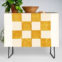 a potted plant sitting on top of a yellow and white checkerboard cabinet