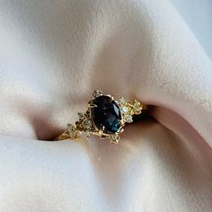 a close up view of a ring on a white cloth with blue and yellow stones