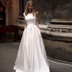 a woman in a white dress standing on the street