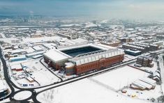 an aerial view of the stadium and surrounding buildings covered in snow on a cold winter day