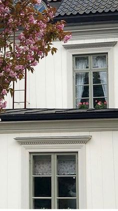 a white house with two windows and pink flowers