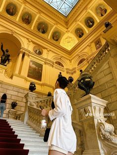 a woman in short shorts is walking up the stairs to an ornate building with paintings on it