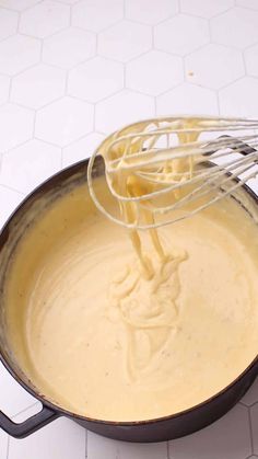 a whisk is being stirred in a skillet on a white tile floor