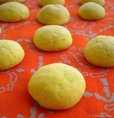 several yellow cookies are lined up on an orange tablecloth with white circles in the middle