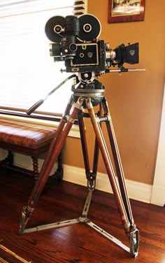 an old fashioned camera sitting on top of a tripod in front of a window