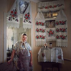 a man standing in front of a window next to a table with flowers on it