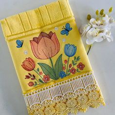 a yellow cloth with flowers and butterflies on it next to a small white flower bouquet