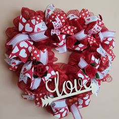 a valentine's day wreath with the word love spelled in white letters on it