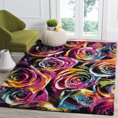 a colorful rug with roses on it in front of a chair and potted plant