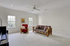 a living room with white carpet and two windows