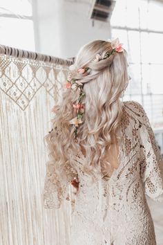 a woman with long blonde hair and flowers in her hair, wearing a white dress