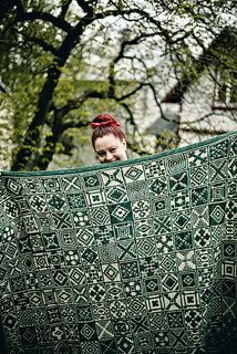 a woman is holding up a green blanket