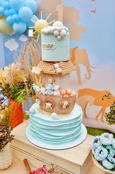 a three tiered cake sitting on top of a table next to balloons and flowers