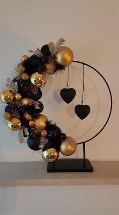 a black and gold wreath with ornaments hanging from it's sides on a shelf