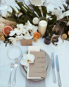 the table is set with silverware and white flowers, candles, and menu cards