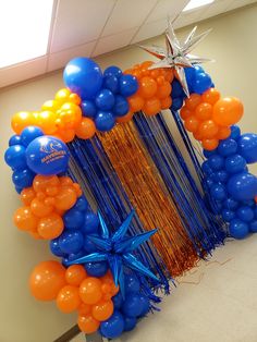 an orange, blue and white balloon arch with star decorations on it's side