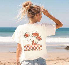 "Design features a scene of palm trees and surf boards at the beach, with sun and seagulls overhead. Below is a checkered stripe, and below that is text \"Find me at the beach\" in a retro bubble font.  Comfort Colors Unisex Tee Info ∙ 100% ring-spun cotton ∙ Medium fabric (6.1 oz/yd² (206.8 g/m ∙ Relaxed fit, and can be sized up for a looser fit ∙ Sewn-in twill label ∙ Designs are Direct to Garment printed, resulting in a soft texture ∙ Please note color shades maybe slightly different to the p Palm Tree Tshirt Design, White Beachy Tops With Palm Tree Print, Surf Crush Aesthetic Outfits, Summer Tops With Palm Tree Print For Surfing, Retro T Shirt Designs, Beach Shirt Design, Find Me, Surf T Shirts, Bubble Font