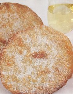 two sugared donuts next to a glass of wine