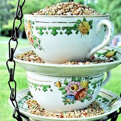 three teacups stacked on top of each other in front of some grass and trees