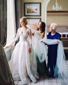 three women in dresses are looking at each other while one woman is holding her hand out