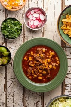 several bowls of food on a table with vegetables and meats in them, including tortilla chips