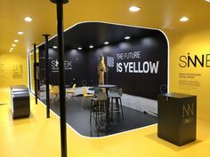 a yellow and black room with chairs, tables and signs on the wall that say snex