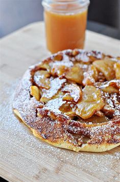 an apple pie with powdered sugar on top next to a jar of orange juice