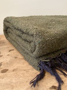 a pile of green blankets sitting on top of a wooden table next to a white wall