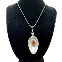 a necklace on a mannequin with a glass pendant hanging from it's side