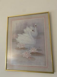 a white swan floating on top of water surrounded by lily pads in a gold frame