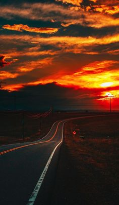 the sun is setting over an empty road