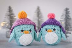 two crocheted stuffed animals wearing hats in front of snow - covered pine trees