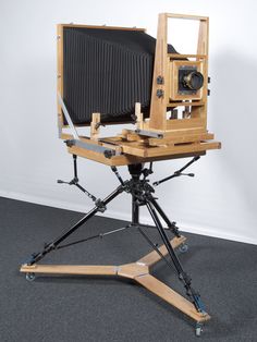 an old camera sitting on top of a tripod in front of a white wall