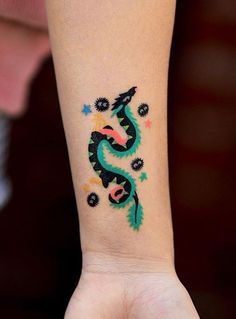 a woman's arm with a dragon tattoo on the left side of her wrist