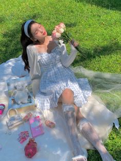 a woman laying on top of a white blanket next to a bouquet of flowers and other items