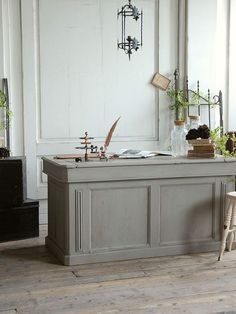 an old fashioned kitchen island with plants on it in front of a white painted wall