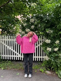 a woman standing in front of a white picket fence with her hands on her head