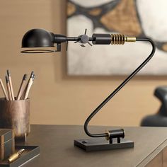 a desk lamp sitting on top of a table next to a cup and pen holder