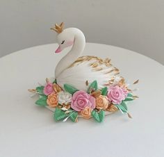 a swan figurine sitting on top of a white table with flowers around it