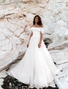 a woman in a white dress standing on rocks