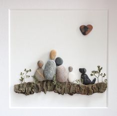 some rocks and plants are sitting on a piece of driftwood in front of a white wall