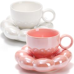 two cups and saucers are sitting next to each other on white plates, one is pink