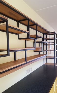 the shelves are lined up against the wall in this room with black counter tops and yellow cabinets