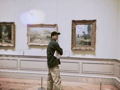 a man is standing in front of some paintings